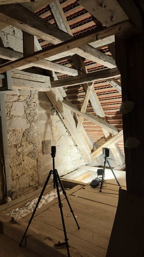 Zwei 3D-Laserscanner auf Stativen erfassen den Dachstuhl eines historischen Gebäudes